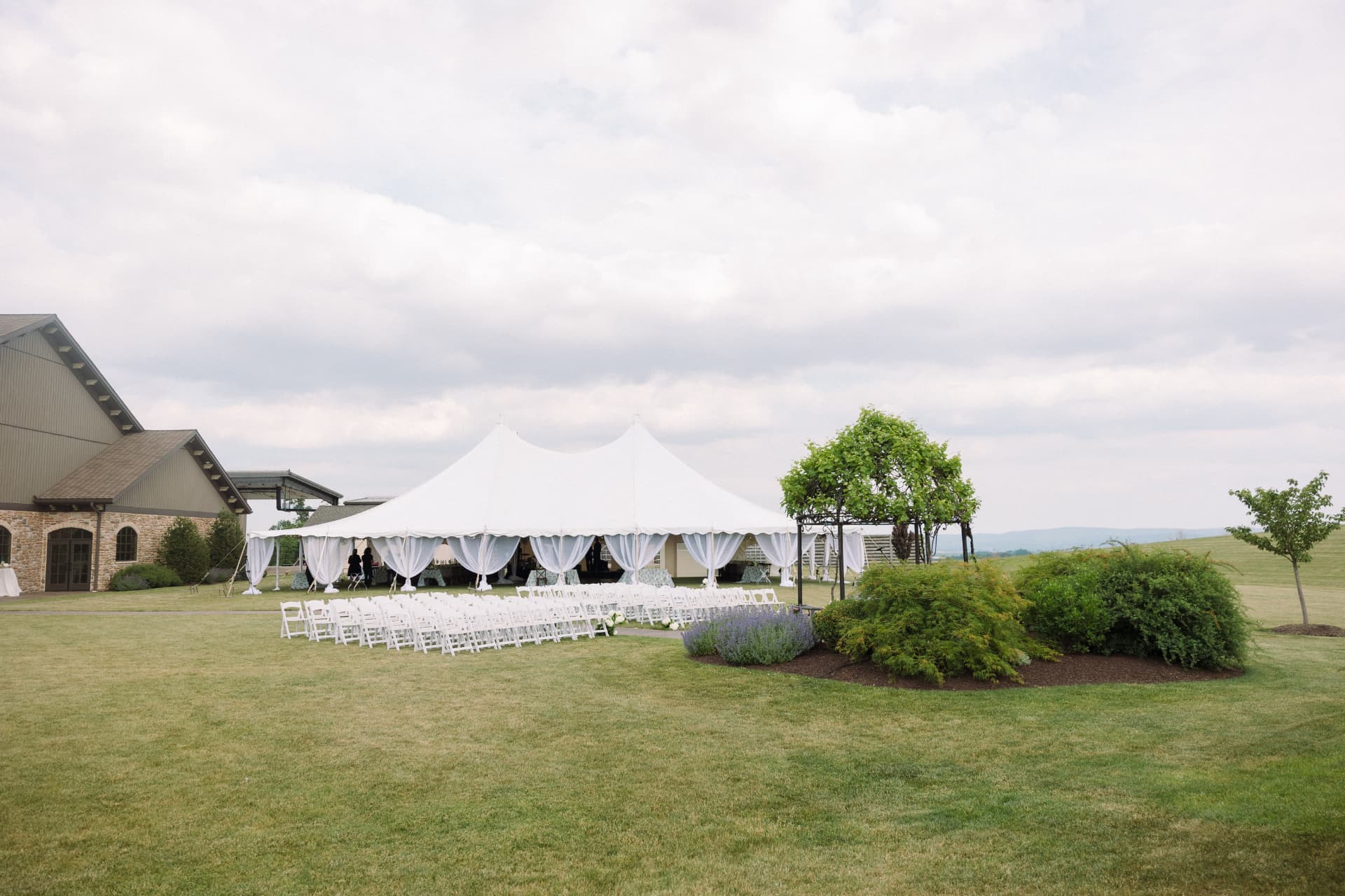 Elegant white sailcloth tent set for an outdoor wedding ceremony
